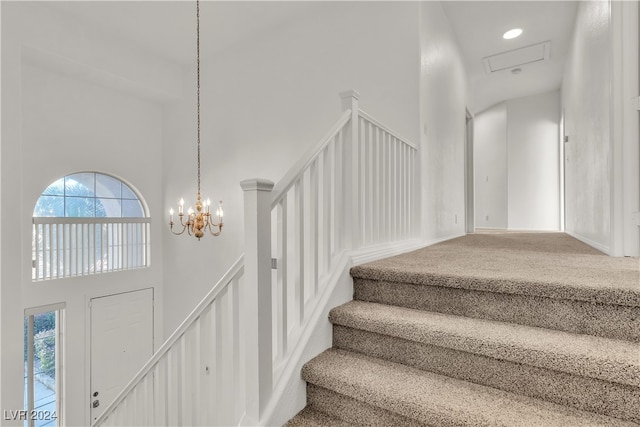 stairway with carpet, a notable chandelier, and a towering ceiling