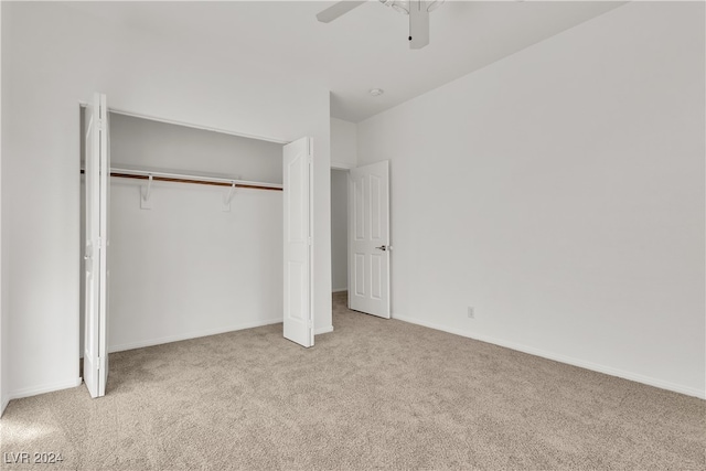 unfurnished bedroom with a closet, light colored carpet, and ceiling fan