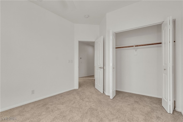 unfurnished bedroom featuring ceiling fan, light colored carpet, and a closet