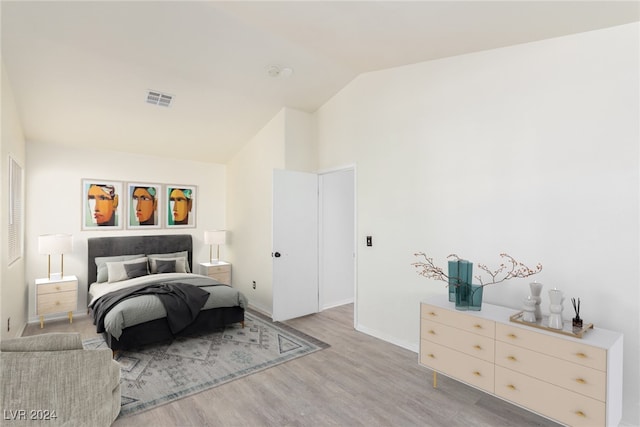 bedroom with light wood-type flooring and vaulted ceiling