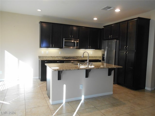 kitchen featuring light tile patterned floors, stainless steel appliances, a kitchen island with sink, and sink