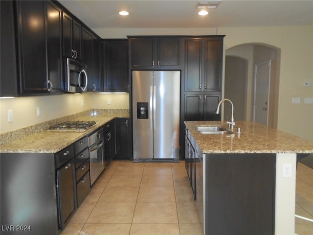 kitchen with light stone counters, sink, light tile patterned floors, and stainless steel appliances