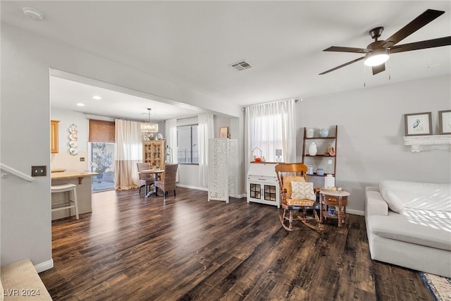 living room featuring ceiling fan with notable chandelier and dark wood-type flooring