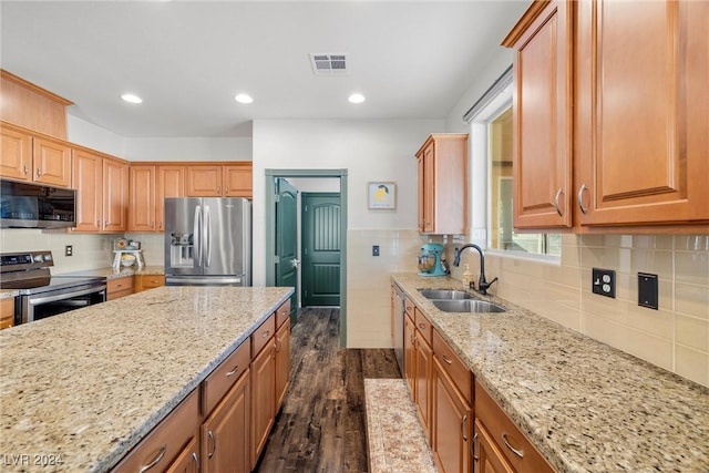 kitchen with stainless steel appliances, sink, light stone counters, and dark hardwood / wood-style floors