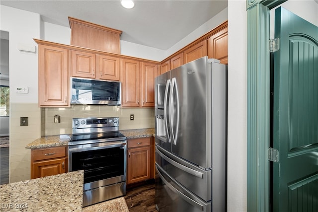 kitchen featuring stainless steel appliances, light stone countertops, and decorative backsplash