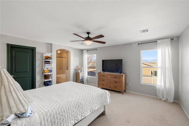 bedroom with multiple windows, ceiling fan, and light colored carpet