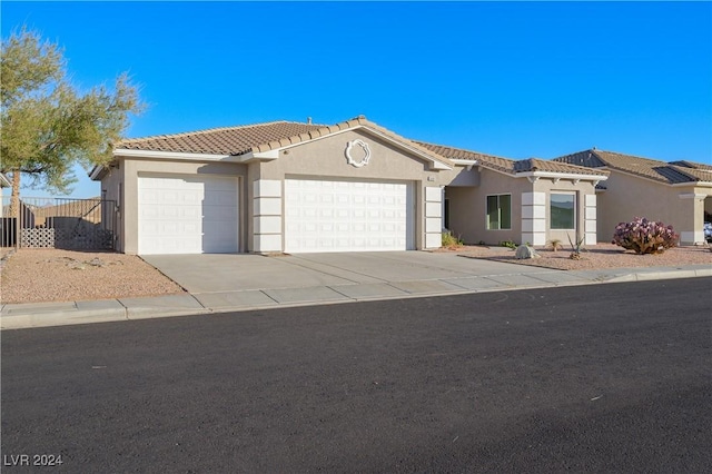 view of front of house featuring fence, a tile roof, concrete driveway, stucco siding, and a garage