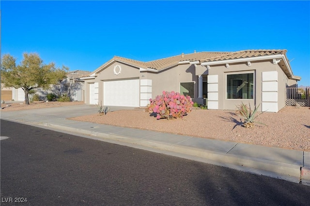 mediterranean / spanish house featuring stucco siding, concrete driveway, an attached garage, and a tile roof