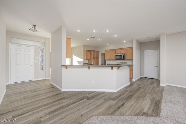 kitchen with kitchen peninsula, a breakfast bar, and light hardwood / wood-style flooring