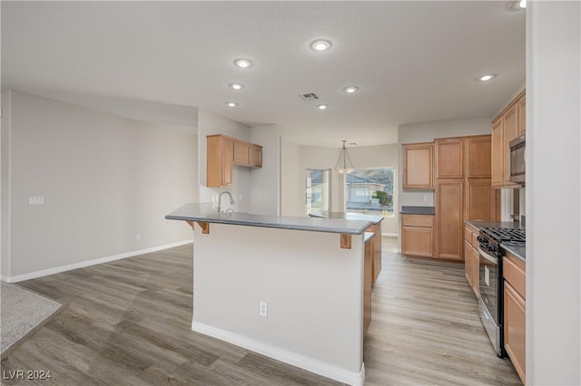 kitchen with stainless steel appliances, a kitchen bar, visible vents, and light wood finished floors