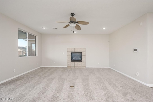 unfurnished living room featuring a tiled fireplace, light carpet, and ceiling fan