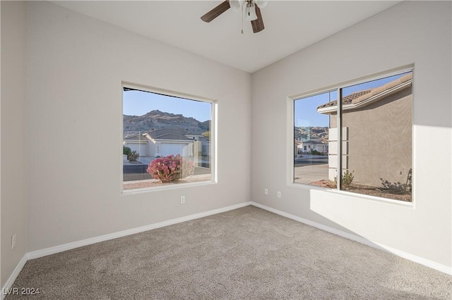 carpeted spare room featuring ceiling fan and a mountain view