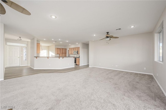 unfurnished living room featuring ceiling fan, carpet, and a healthy amount of sunlight