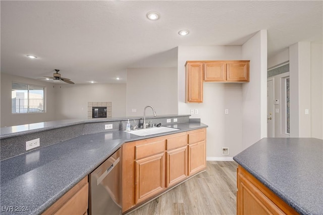 kitchen with light hardwood / wood-style flooring, a tiled fireplace, stainless steel dishwasher, ceiling fan, and sink