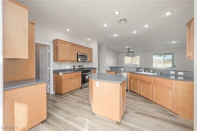 kitchen featuring a peninsula, ceiling fan, a sink, light wood-style floors, and appliances with stainless steel finishes