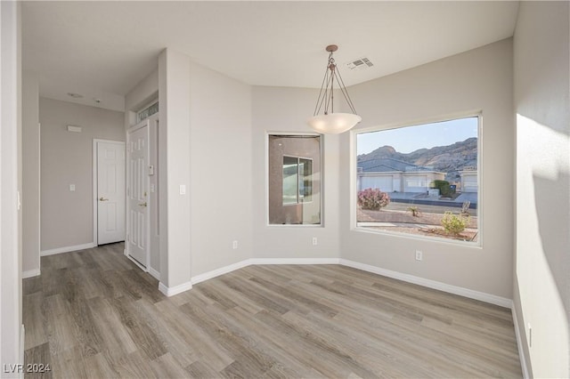 unfurnished dining area featuring hardwood / wood-style flooring and a mountain view