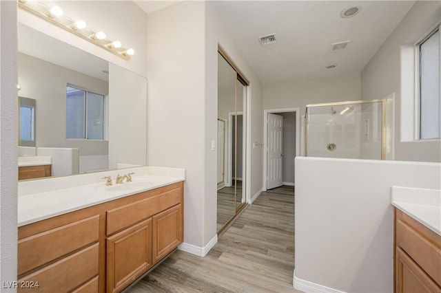 bathroom with visible vents, a stall shower, wood finished floors, baseboards, and vanity