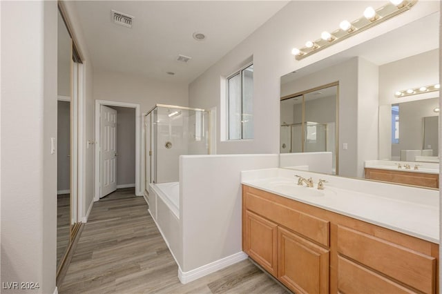 bathroom featuring vanity, wood finished floors, visible vents, and a stall shower