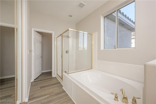 bathroom featuring visible vents, baseboards, a garden tub, a stall shower, and wood finished floors