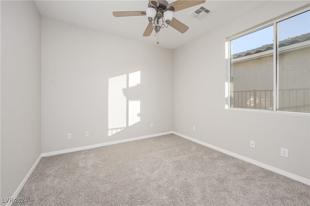 carpeted empty room with visible vents, baseboards, and a ceiling fan