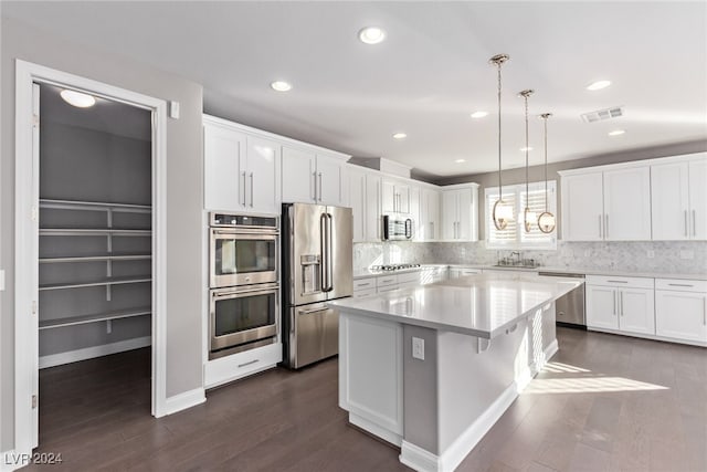 kitchen with white cabinets, hanging light fixtures, a kitchen island, and stainless steel appliances