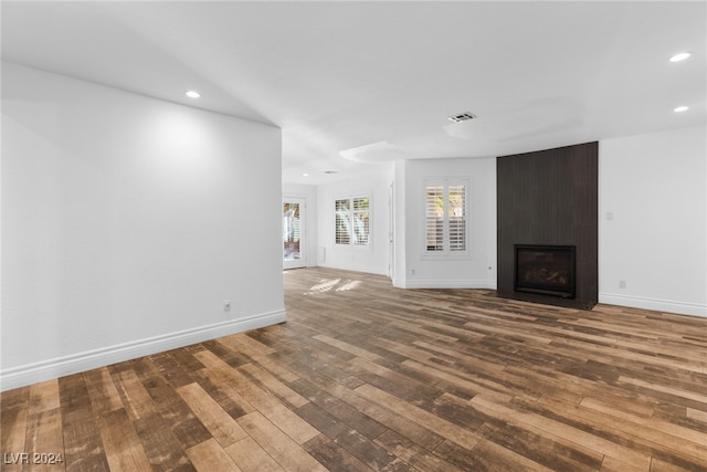 unfurnished living room featuring hardwood / wood-style floors and a large fireplace