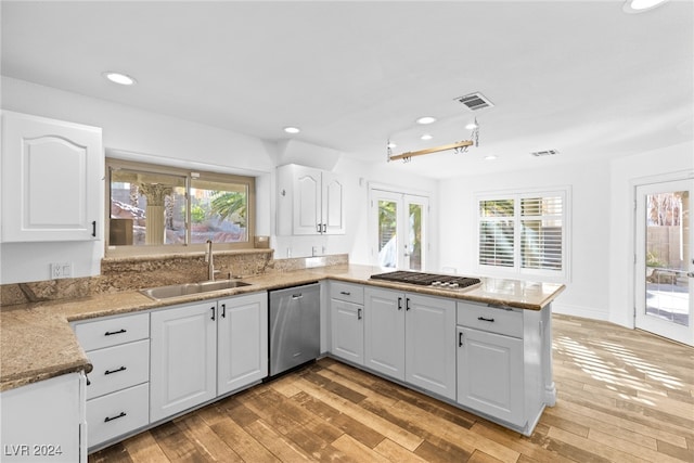 kitchen featuring white cabinetry, sink, kitchen peninsula, appliances with stainless steel finishes, and light wood-type flooring