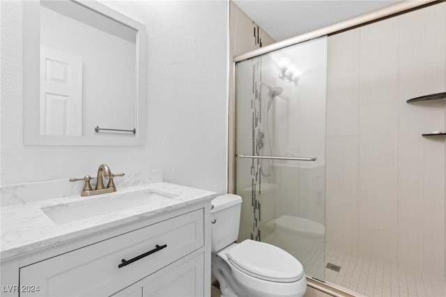 bathroom with vanity, toilet, and a shower with door