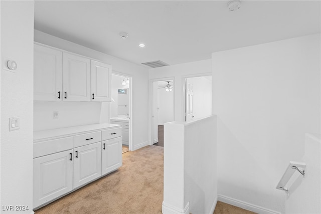 interior space featuring light colored carpet, white cabinetry, and ceiling fan