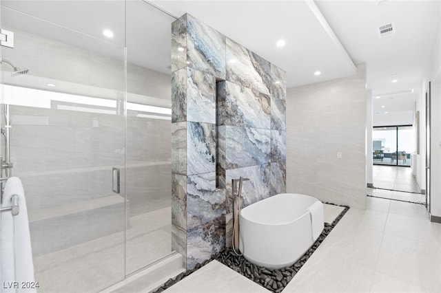 bathroom featuring tile patterned flooring, tile walls, and independent shower and bath