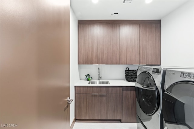 washroom with washing machine and clothes dryer, sink, and cabinets