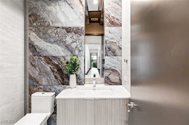 bathroom with toilet, tile walls, and sink