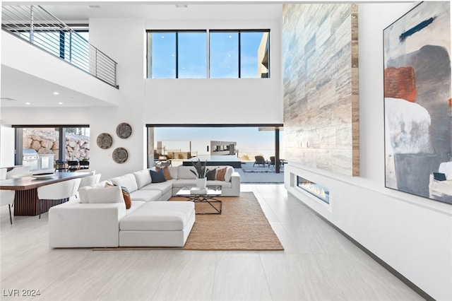 tiled living room with plenty of natural light, a large fireplace, and a towering ceiling