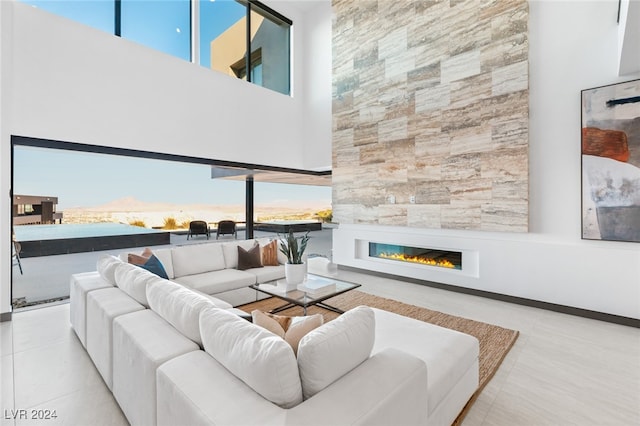 living room with a large fireplace, light tile patterned floors, and a high ceiling