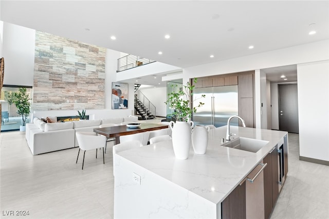 kitchen with dishwasher, a center island with sink, light stone counters, and sink