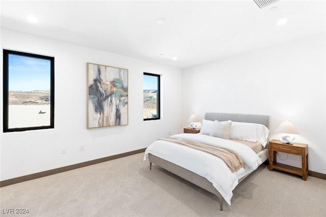 bedroom with light colored carpet and multiple windows