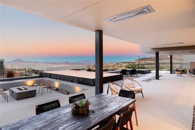 patio terrace at dusk featuring a mountain view and an outdoor living space with a fire pit