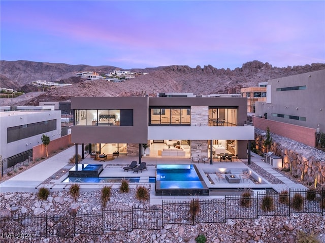 back house at dusk with a mountain view and an outdoor hangout area