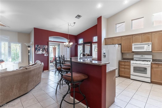 kitchen with a chandelier, a wealth of natural light, pendant lighting, and white appliances