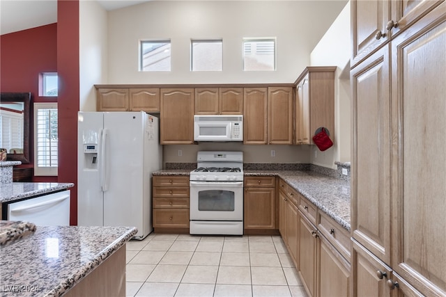 kitchen with a wealth of natural light, light tile patterned flooring, and white appliances