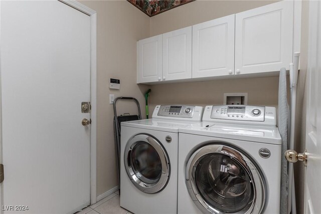 laundry room featuring washing machine and clothes dryer, light tile patterned floors, and cabinets