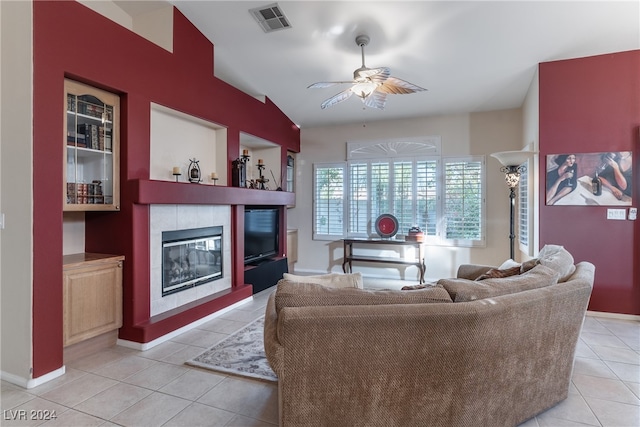 tiled living room featuring ceiling fan and a tiled fireplace