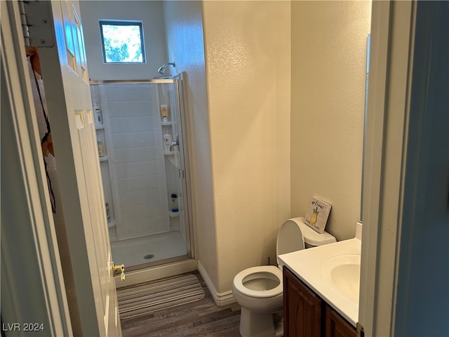 bathroom with hardwood / wood-style floors, vanity, toilet, and a shower with shower door