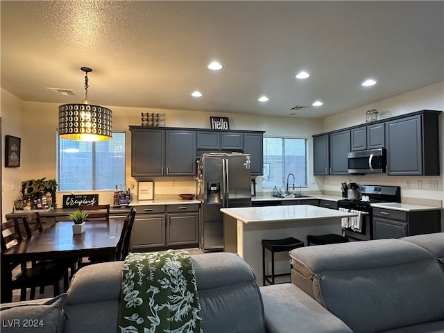 kitchen featuring black range with gas cooktop, sink, fridge with ice dispenser, a center island, and hanging light fixtures