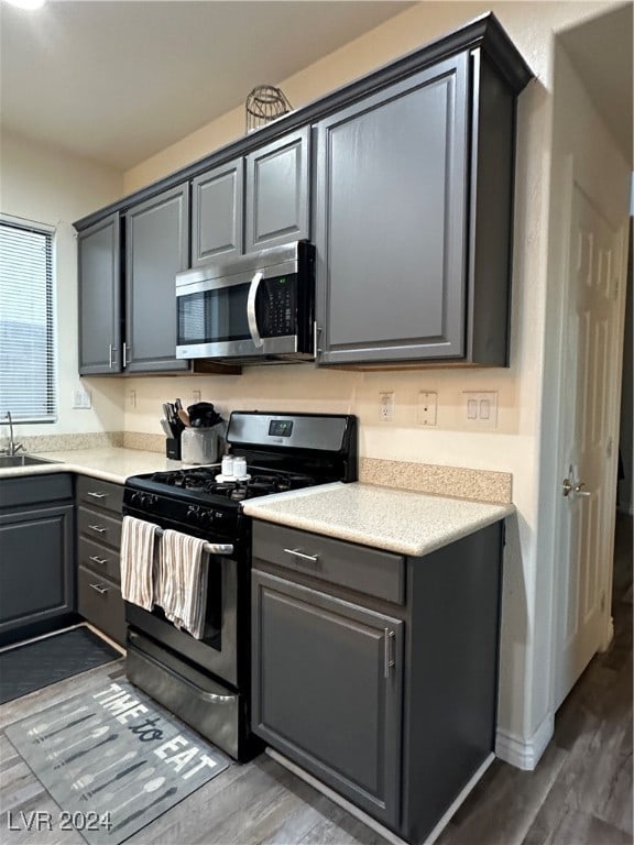 kitchen featuring dark hardwood / wood-style floors, gray cabinets, black gas stove, and sink