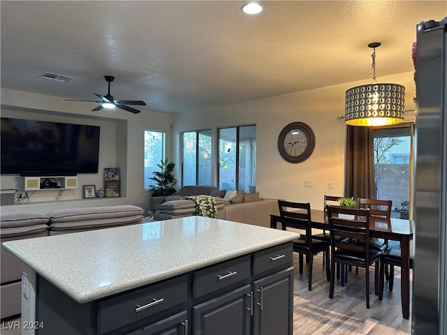 kitchen featuring light wood-type flooring, refrigerator, ceiling fan, decorative light fixtures, and a center island