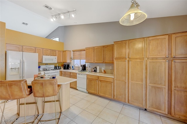 kitchen with light brown cabinets, a kitchen island, white appliances, a breakfast bar, and light tile patterned floors