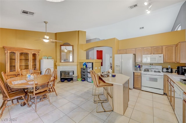 kitchen with ceiling fan, a center island, white appliances, a kitchen bar, and light tile patterned flooring