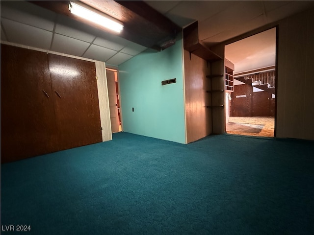 basement featuring a drop ceiling and carpet