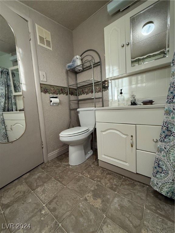 bathroom featuring a textured ceiling, vanity, and toilet